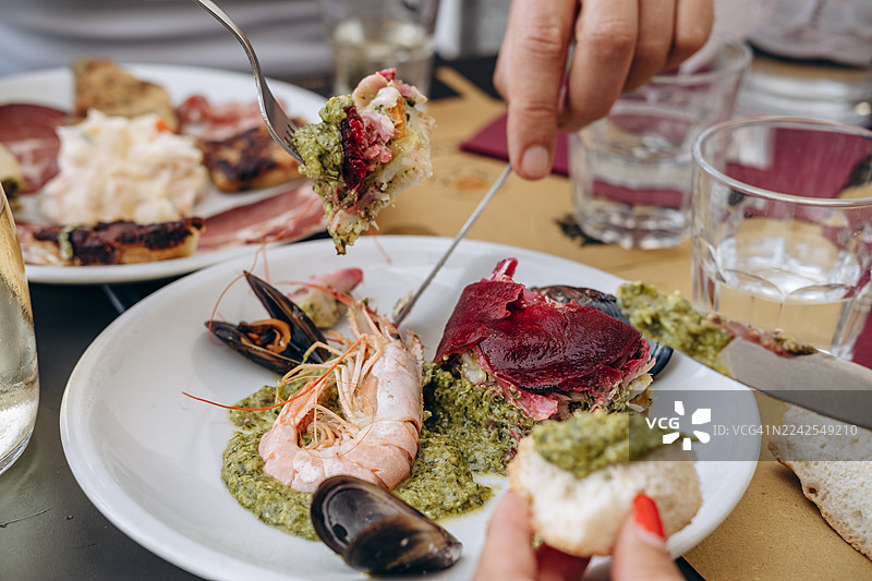 餐桌上享用精致的海鲜美食，包括鲜虾、贻贝和色彩鲜艳的香蒜酱。图片素材