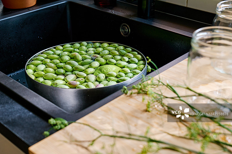 绿色的橄榄漂浮在厨房水槽的水中图片素材