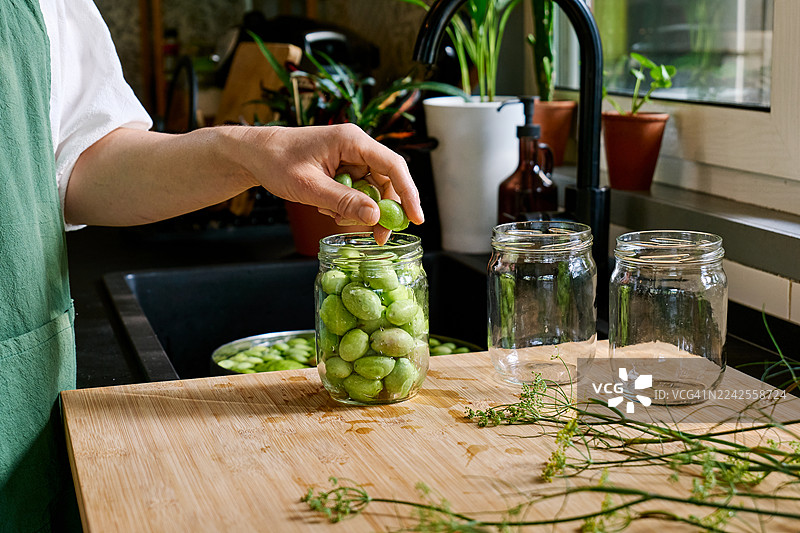 女性手将绿色橄榄装满玻璃碗图片素材