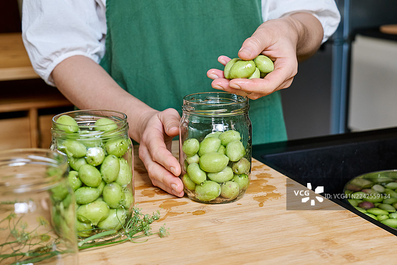 女性双手将绿色橄榄装满玻璃碗图片素材