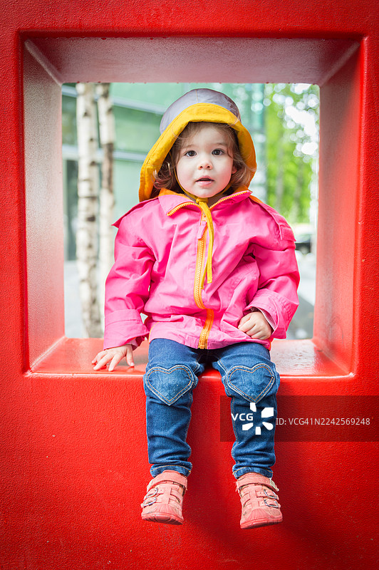 18个月大的小女孩坐在红色的混凝土方块上图片素材