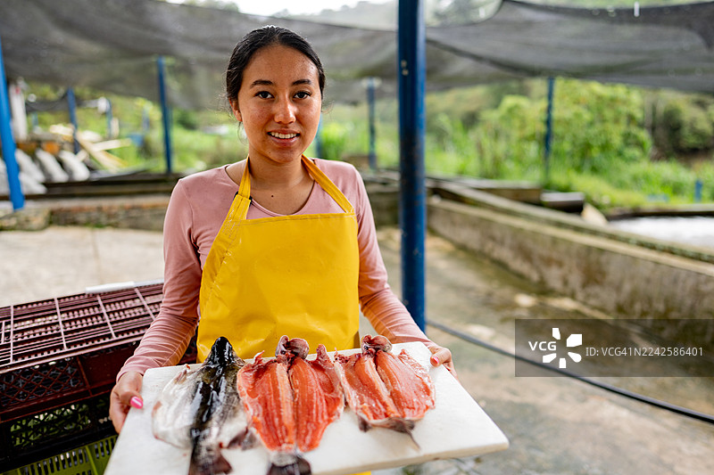 在桑坦德省皮耶德奎斯塔的一个渔场，一位少女肖像，她手中拿着新鲜的鳟鱼图片素材