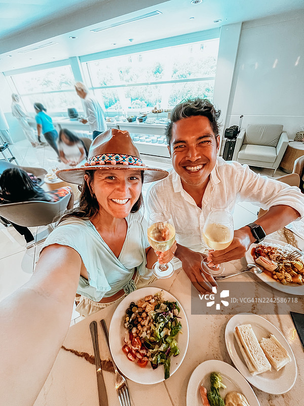 一对情侣在午餐时举杯畅饮葡萄酒，面带微笑图片素材