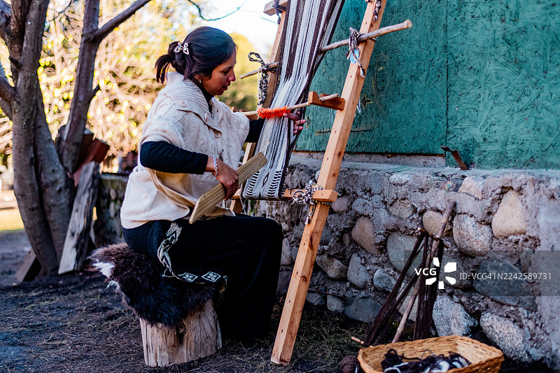 阿根廷圣马丁德洛斯安第斯地区，一位中年马普切妇女正在制作传统的蓬丘披肩图片素材