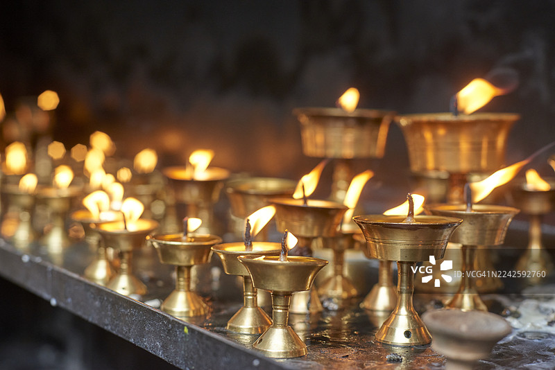 尼泊尔寺庙里燃烧的黄油灯，火焰明亮图片素材