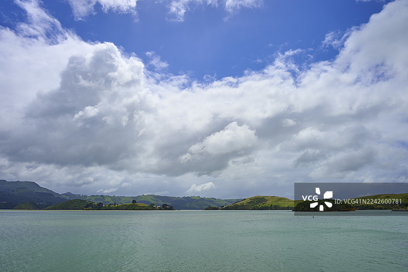 越过水面望向绿色的山丘，天空多云，地点：布罗德湾，但尼丁，奥塔哥，南岛，新西兰图片素材