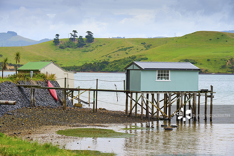 新西兰南岛但尼丁奥塔哥布罗德湾，绿色小山旁栈桥上的小屋风景图片素材