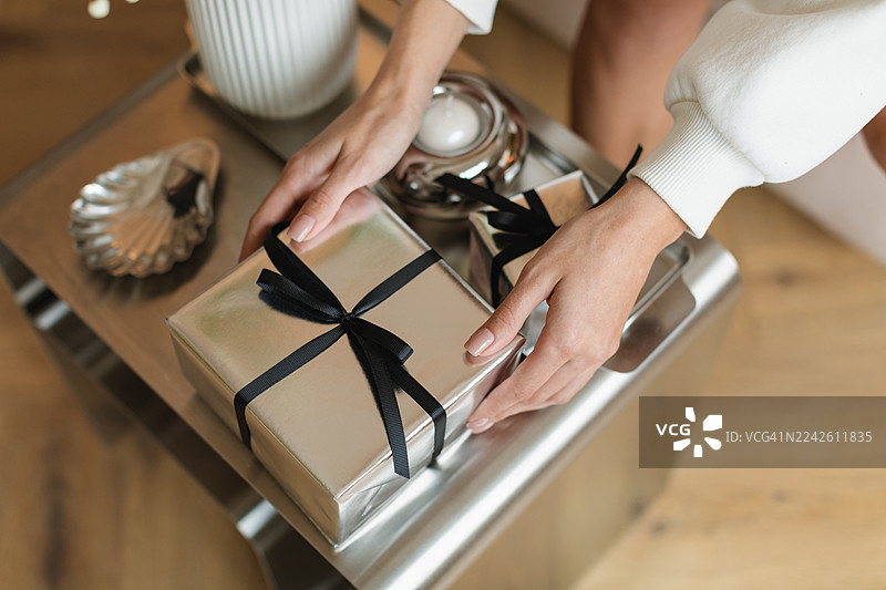 俯视近景，一名年轻女子正伸手去拿咖啡桌上的礼物图片素材