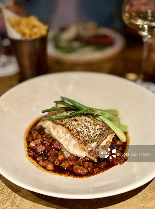 烤鳕鱼近景，配以豆子、培根和红酒酱图片素材