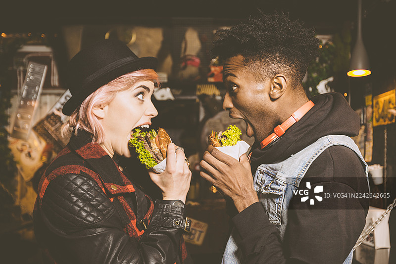 时髦的情侣在酒吧里吃汉堡图片素材