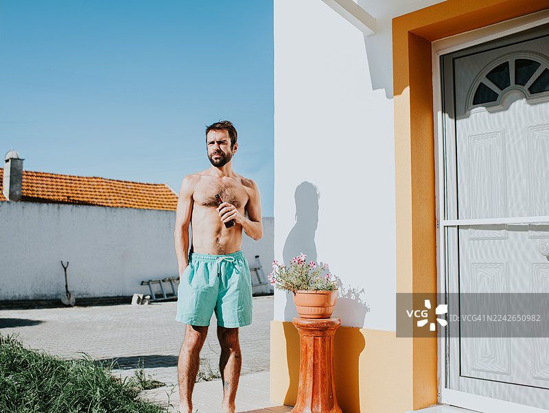 阳光明媚的一天，一个男人站在户外，手中拿着一杯饮料图片素材