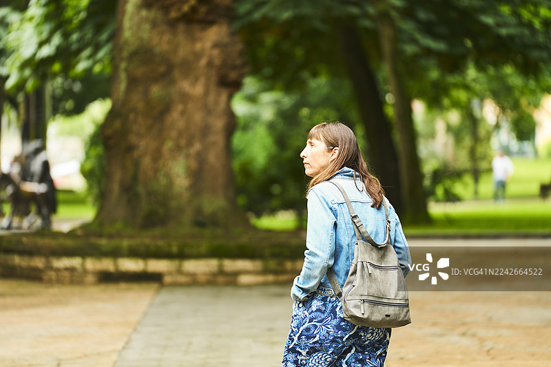 一位女士在公园里散步，享受着大自然和新鲜空气图片素材