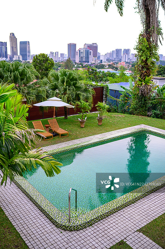 带葱郁绿植和吉隆坡天际线景观的私人泳池绿洲图片素材
