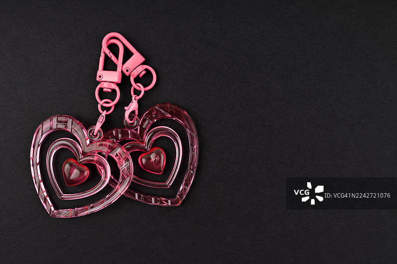 黑色背景上的粉色双心钥匙扣，附有留白位置。图片素材