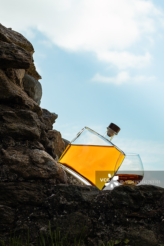 倾斜的格拉巴酒瓶与酒杯置于户外图片素材