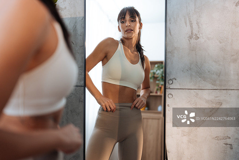 一位健美的女性在镜子前为家庭健身做准备图片素材
