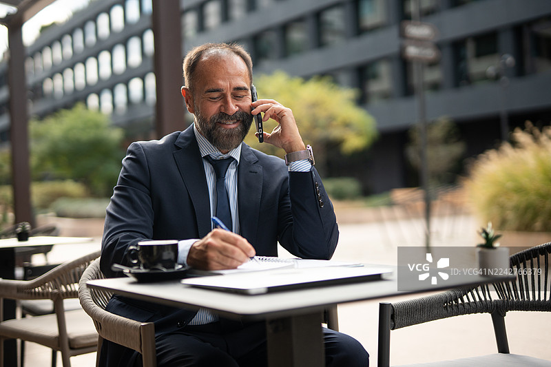 成熟的商人一边打电话一边查看笔记图片素材