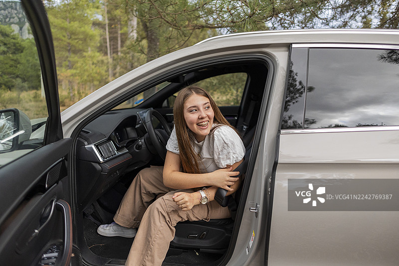 一名少女在车内享受公路旅行冒险，脸上带着笑容图片素材