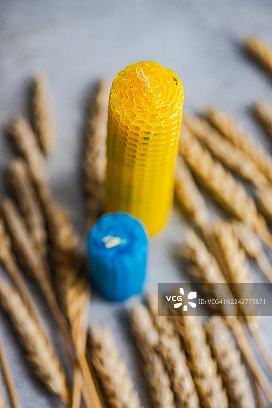 桌子上摆放着蓝色和黄色的自制蜡烛，周围环绕着麦穗，以示对乌克兰的支持。图片素材