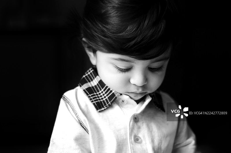 一个年轻印度男孩的黑白特写肖像照。图片素材