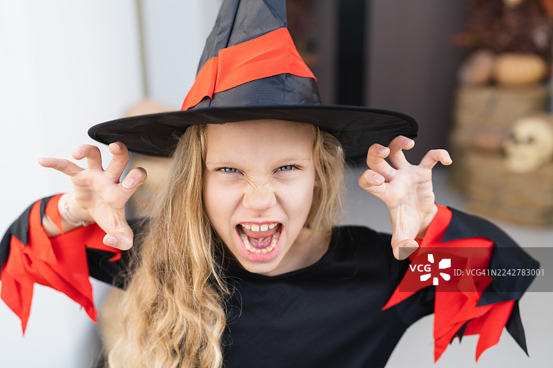 穿着万圣节女巫服装的女孩，做出恐怖表情的肖像图片素材