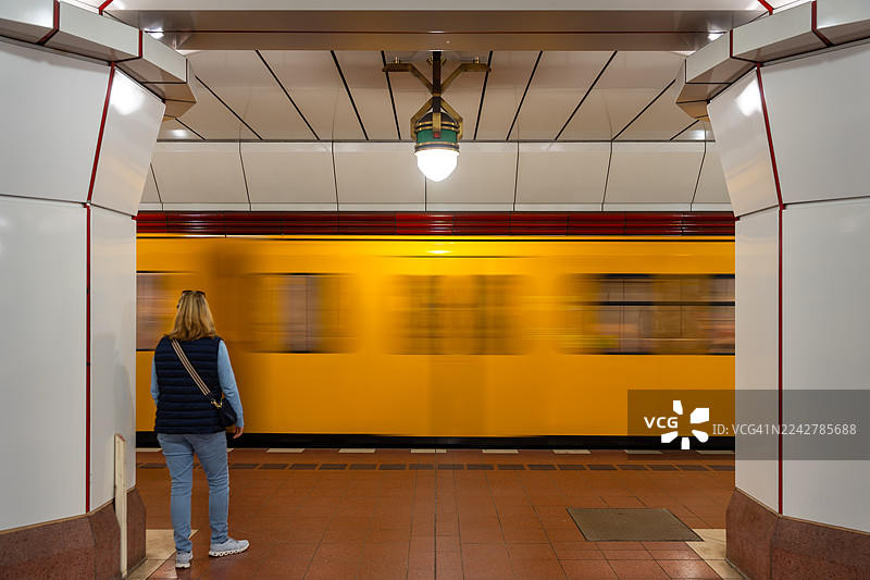 一位女性站在站台上，迎接即将到来的地铁图片素材