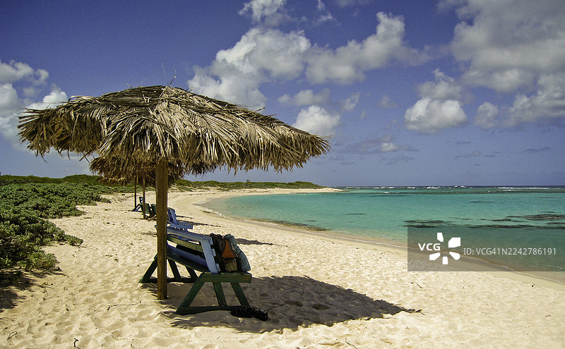 英属维尔京群岛阿内加达岛的海滩，配有蓝天、翠绿的大海和沙滩伞。图片素材
