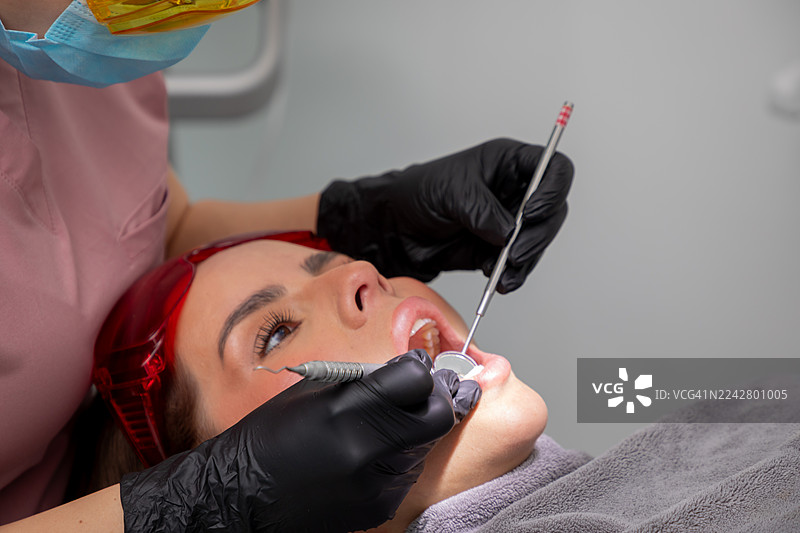 在现代诊所中，牙医在进行牙科检查时检查患者的牙齿，重点关注口腔卫生和健康图片素材