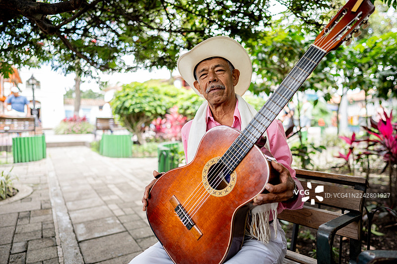 哥伦比亚麦德林一位年长男子弹奏原声吉他的肖像图片素材