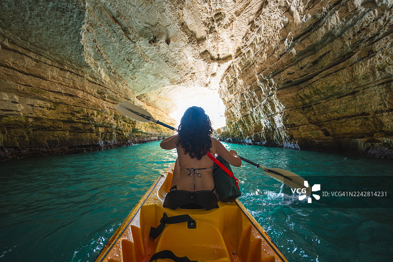 在意大利普利亚地区，乘皮划艇穿越阳光照射下的海蚀洞图片素材