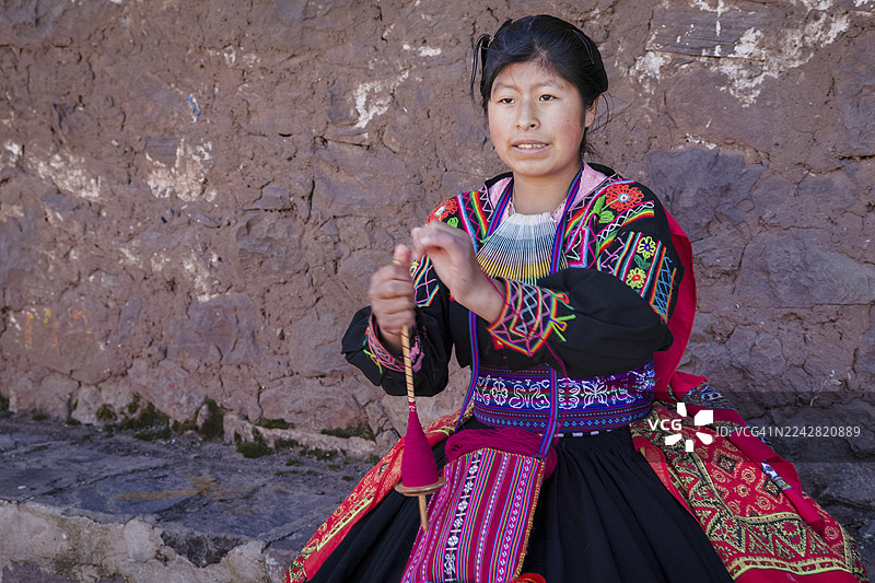 秘鲁的的喀喀湖塔基莱岛上一位年轻女子正在手工纺羊毛图片素材