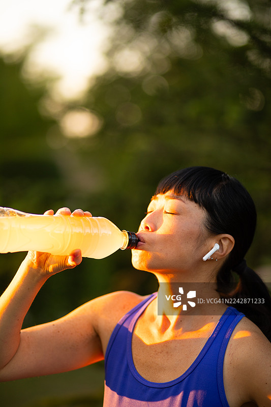运动后在户外饮用运动饮料的女性图片素材