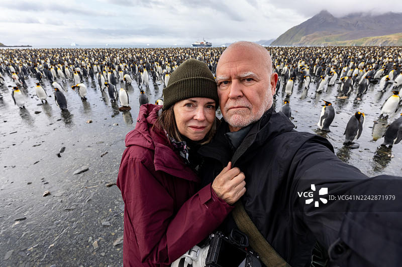一对成熟的夫妇在帝企鹅前图片素材