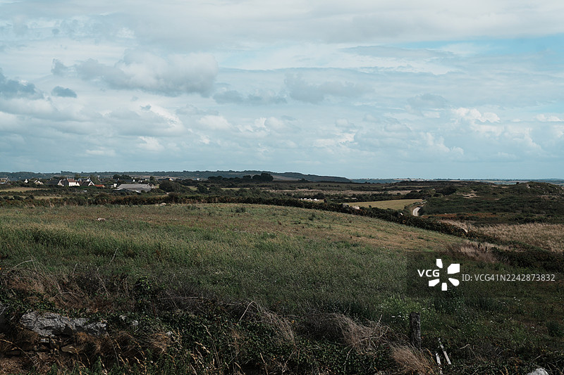 广阔的风景，绿色的田野，远处的房屋，多云的天空图片素材