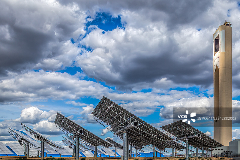 多云天空下的太阳能热发电站，配有中央塔和抛物面槽式集热器，西班牙图片素材