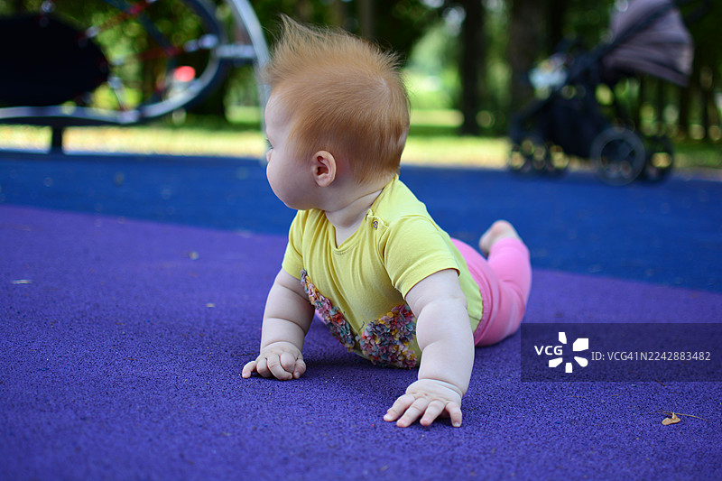 可爱的婴儿在户外的紫色瑜伽垫上爬行图片素材