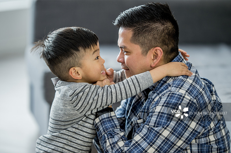 爸爸和儿子在家中深情拥抱，表达爱意、亲情和喜悦图片素材