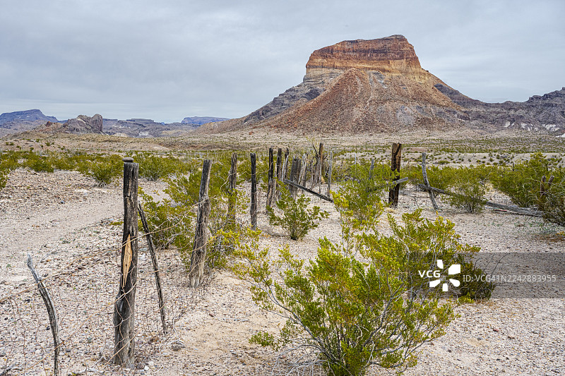 阴天下的雄伟孤山沙漠风光，点缀着古老的木栅栏和灌木丛，美国大弯国家公园图片素材