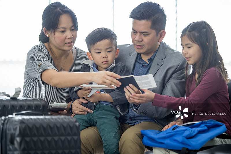 一家四口亚洲家庭在机场一同出行，查看护照和机票图片素材