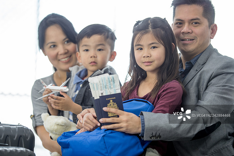 快乐的亚洲家庭在机场，手持护照和登机牌，准备旅行图片素材