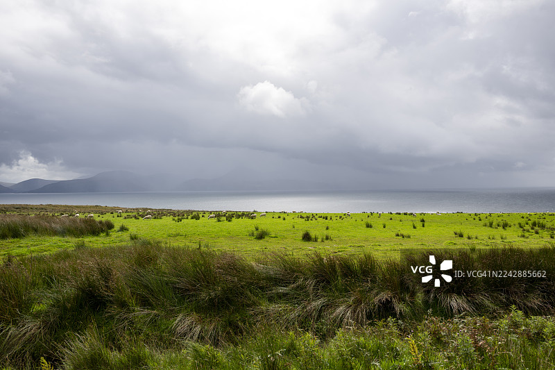 英国阿盖尔和比特郡海边绿野风光，远眺群山，天空多云图片素材