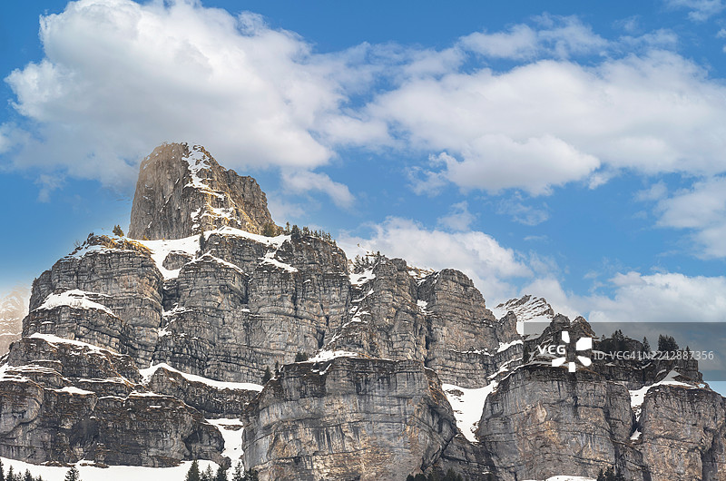 奥地利因斯布鲁克哈费莱卡，在晴朗的蓝天下和白云朵朵映衬下，雄伟的阿尔卑斯山岩层覆盖着白雪图片素材