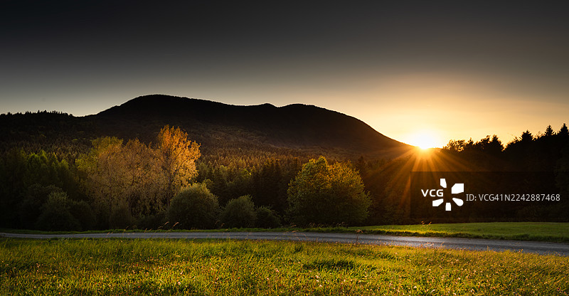 波兰杜克拉，金色日落下的山地景观，包含森林和草地，展现大自然的壮丽之美图片素材