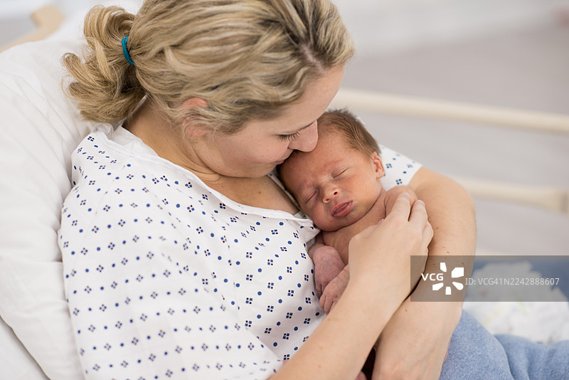 医院病房里，新生儿被母亲温柔地抱在怀中，温馨动人图片素材