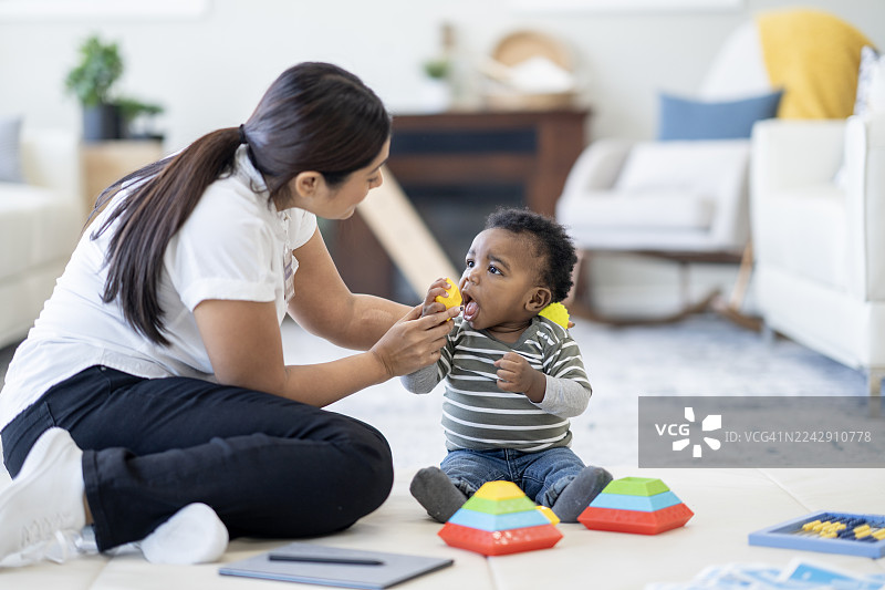 今日，一位充满爱心的黑人母亲在家中的游戏室里，与色彩缤纷的玩具一同玩耍，陪伴着她的宝宝。图片素材