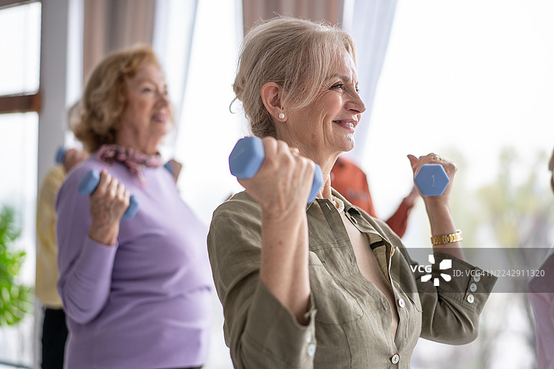 老年人团体健身，手持哑铃，笑容满面图片素材