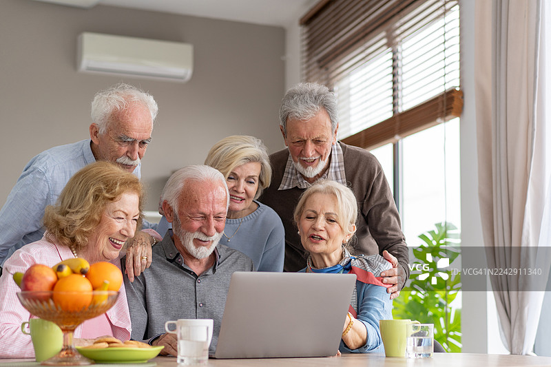 一群快乐的老年人围着笔记本电脑分享时光图片素材