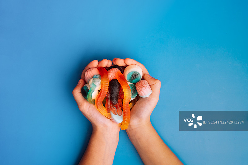 蓝色背景下手持万圣节什锦软糖图片素材