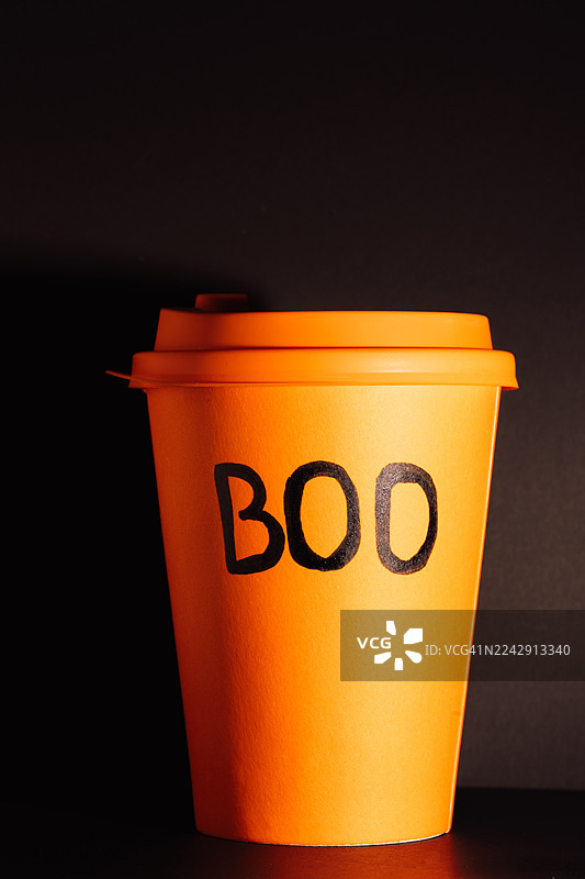 黑色背景上的橙色外卖杯，杯上印有BOO字样图片素材