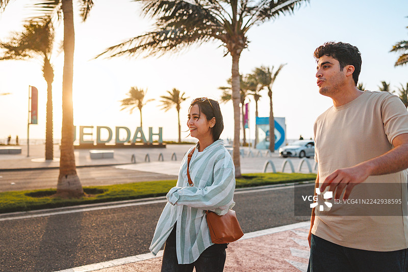 一群快乐的年轻人在吉达地标旁散步图片素材